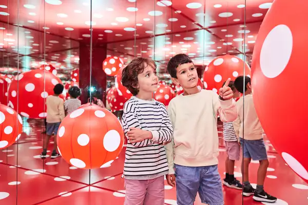 Two children enjoy a red and white polka dot installation by Yayoi Kusama