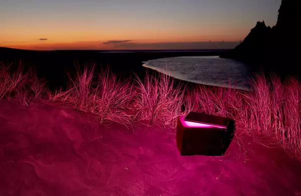 An open capsule on a beach at night. The image has a pink hue.