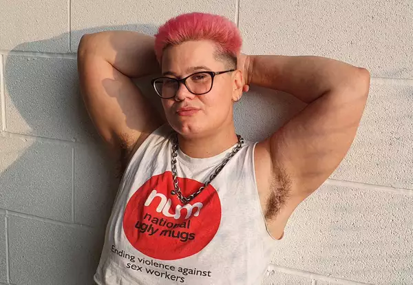 Photo of DJ Duckdown with arms raised against a breezeblock wall