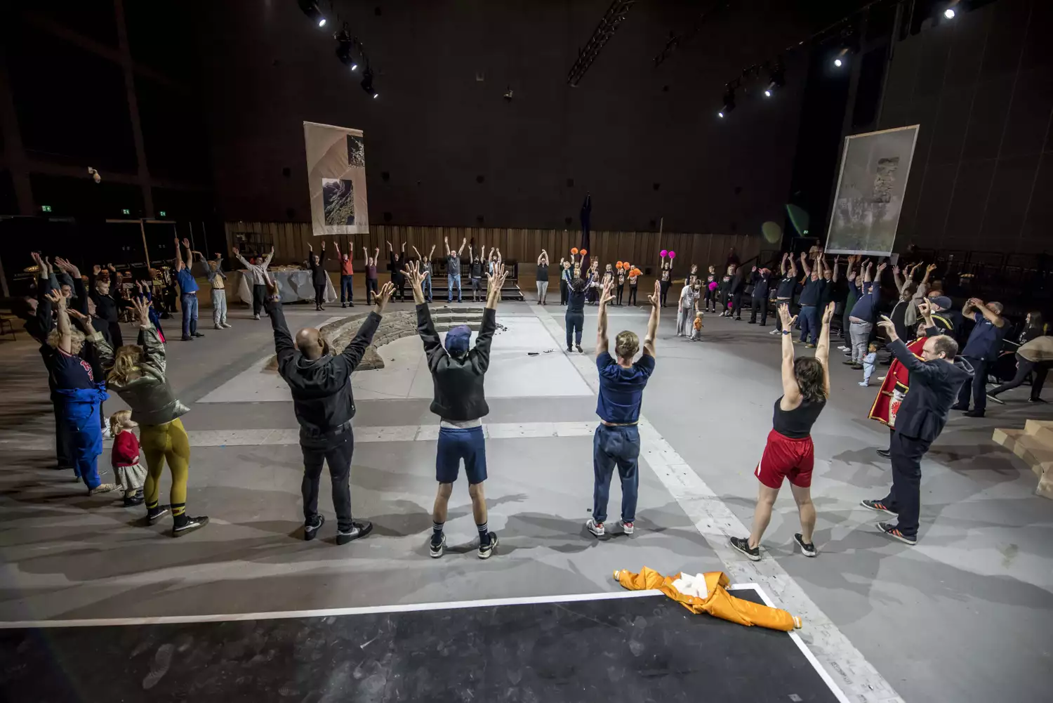 A large group of people with their hands in the air stood in a circle around a clay installation – for the June 2024 Artist Takeover