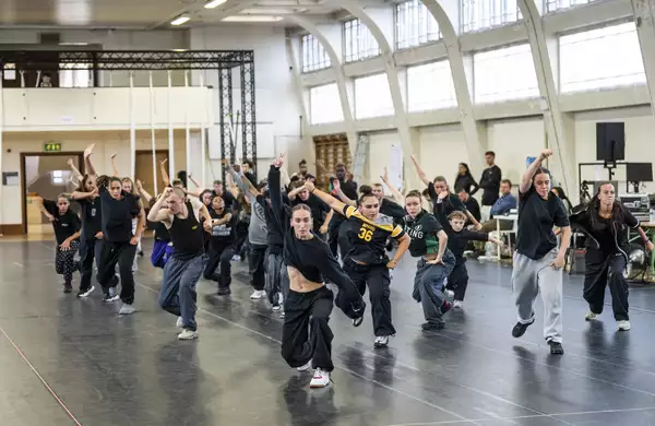 Dancers for Free Your Mind with one arm raised in rehearsals