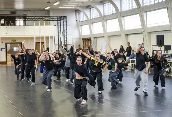 Dancers for Free Your Mind with one arm raised in rehearsals
