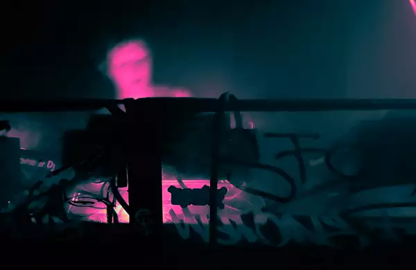 A person DJs in a booth decorated with graffiti and stickers