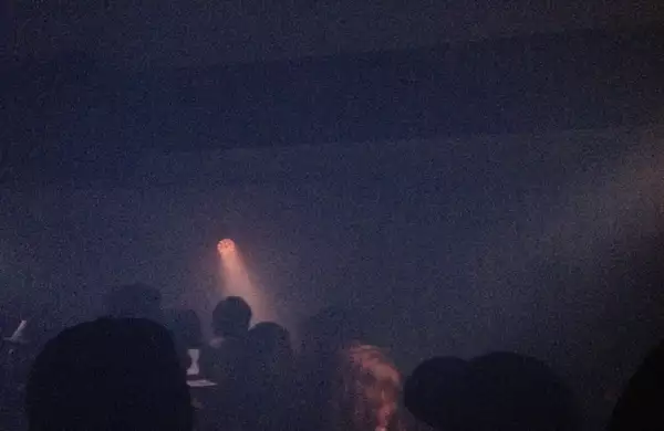 A single spotlight illuminates a dancefloor at a rave