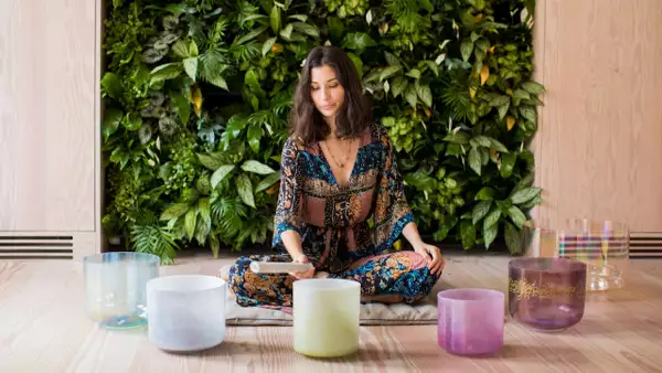 A person leading a sound bath in front of a wall of grass