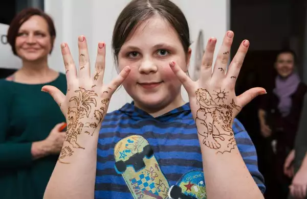 Young girl holding up her hands covered in henna tattoos