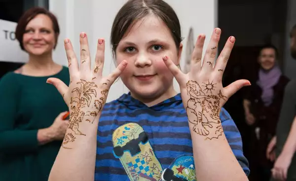Young girl holding up her hands covered in henna tattoos