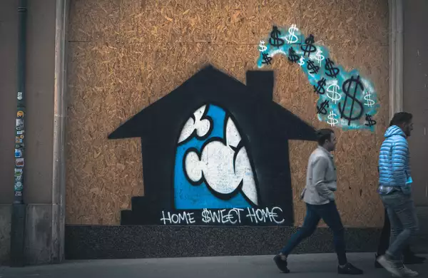 Photo of graffiti that reads Home Sweet Home in front of a house and clouds