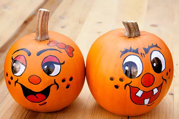 Photo of two pumpkins with faces drawn on
