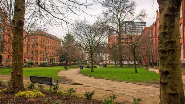 Benches and greenery in Sackville Gardens overlooked by red brick buildings