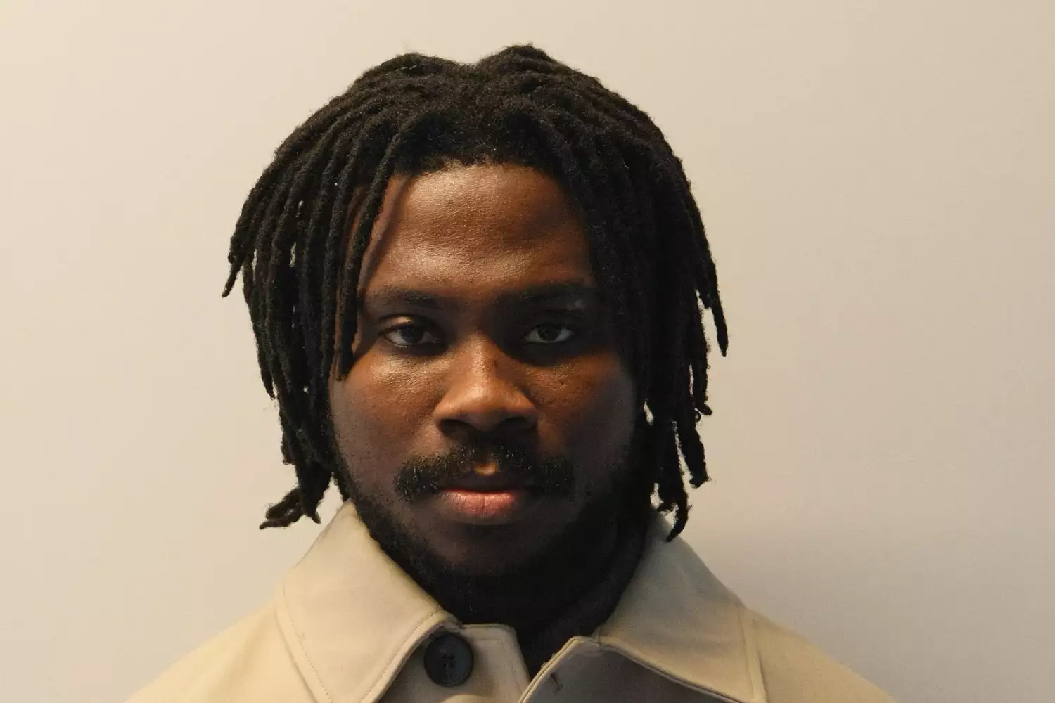 Headshot of Hakeeb Ibrahim on a beige backgroud