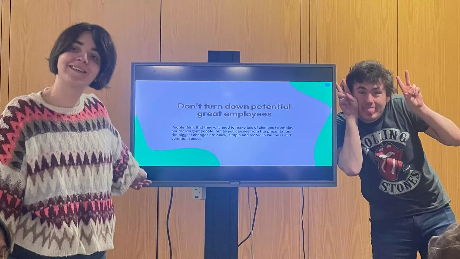 Two people stood in front of a screen which says 'Don't turn down potential great employees'