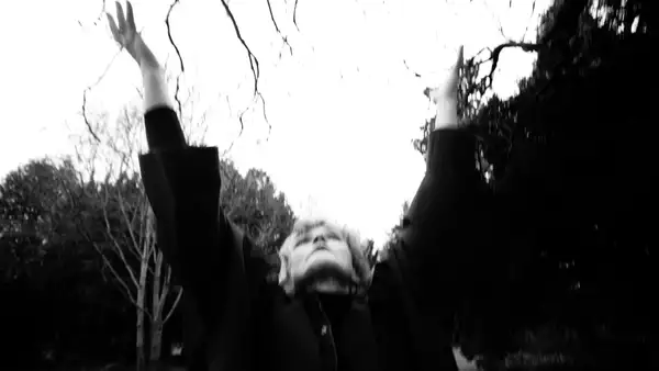 black and white, blurry photo of Maxine Peake looking up at the sky with her hands in the air